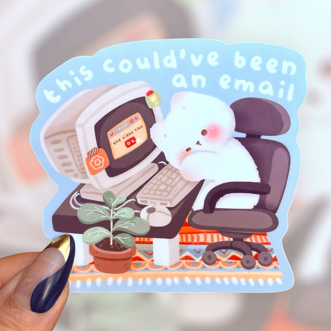 A cute matte vinyl sticker of a fluffy white bear sitting in a black office chair at a retro computer with the phrase “This could’ve been an email” written above. The bear looks tired as it ends a video call, with a small potted plant and colorful rug adding cozy touches to the scene.